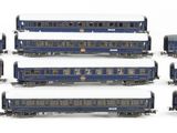 six blue train cars sitting next to each other on a white surface