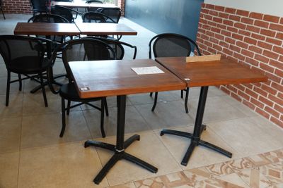 tables and chairs in a restaurant with a brick wall in the background