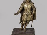 statue en bronze représentant un homme muni d'une canne et coiffé d'un chapeau, posée sur un socle