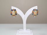 paire de boucles d'oreilles en oplite, saphir et citrine, présentées sur un socle blanc