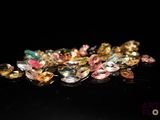 a close up of a pile of multi colored gems on a black surface