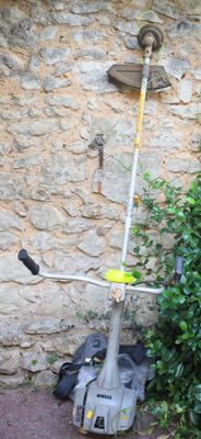 a small pole with a yellow handle next to a bush