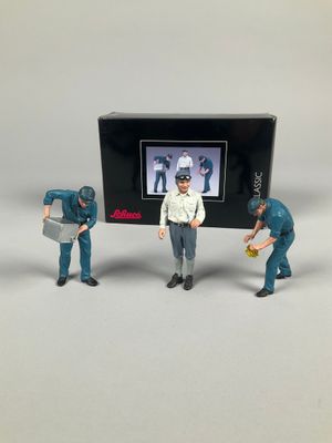 three figurines of men in blue uniforms are standing in front of a television