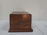 small wooden box on white surface with white wall in background