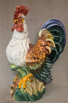 un coq en céramique posé sur une plante