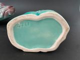 a small ceramic figurine of a fish and a small ceramic figurine of a fish on a table