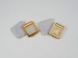 deux bijoux en or et en argent posés sur une surface blanche