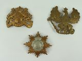 three gold brooches of various shapes and sizes on a white surface