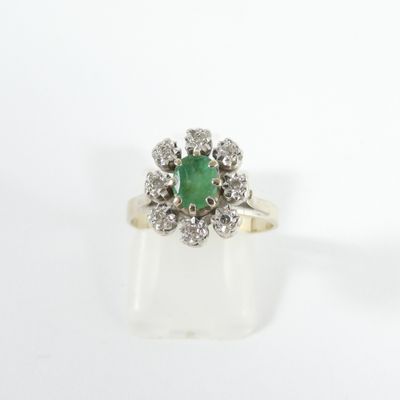 gros plan d'une bague avec une pierre verte entourée de diamants blancs