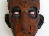 un masque marron aux yeux rouges sur un fond blanc
