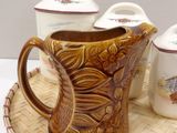 a brown pitcher sitting on top of a tray next to three cups