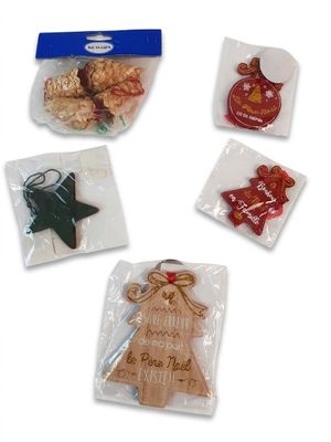 quatre décorations de Noël dans des sachets, posées sur une surface blanche