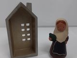a figurine of a woman holding a book next to a house