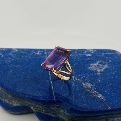 a close up of a ring with a purple stone on top of a blue stone
