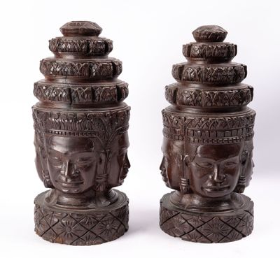 paire de têtes de Bouddha sculptées dans le bois, posées sur des socles, sur fond blanc