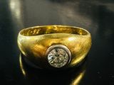 bague en or jaune sertie d'un diamant sur un fond noir