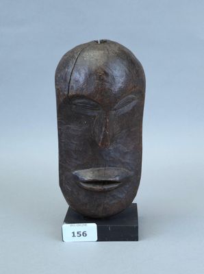 un gros plan sur une sculpture en bois représentant un visage, posée sur un socle