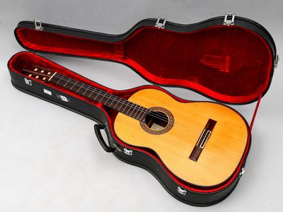 une guitare dans un étui, posée sur une surface blanche