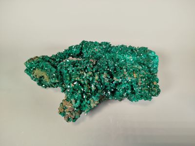 a close up of a cluster of green crystals on a white surface