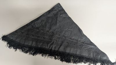 someone is holding a black umbrella with a black fringe on it
