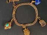 un gros plan sur un bracelet en or orné de breloques et d'une cage à oiseaux
