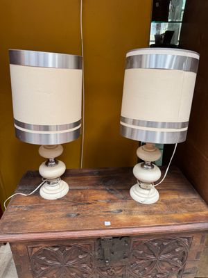 two lamps on a wooden table with a brown wall in the background