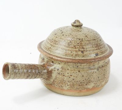a small brown pot with a handle on a white surface