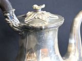 a silver tea pot on a table with a spoon in it
