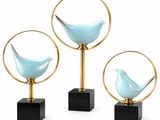 three blue glass birds sitting on top of black marble bases