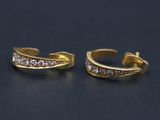 une paire de boucles d'oreilles en or et diamants sur une surface noire