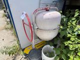 deux seaux d'eau à côté d'une bonbonne de propane, contre le mur d'un immeuble