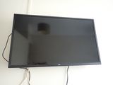 a flat screen tv sitting on the wall next to a lamp