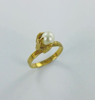 gros plan d'une bague en or contenant une perle
