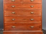 an old wooden chest of drawers on wheels against a gray background