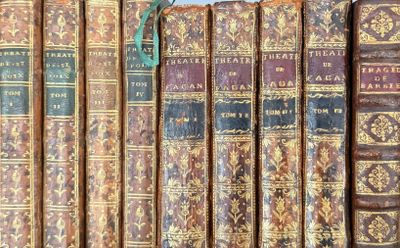 several old books are lined up on a shelf in a library