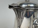 a silver coffee pot with a lid on a table
