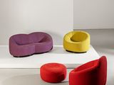 Plusieurs chaises de différentes couleurs sont disposées sur une estrade blanche dans une pièce