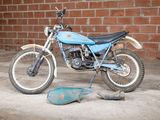a blue dirt bike parked in front of a brick wall