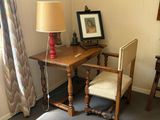 a small desk with a lamp and a chair in the corner