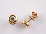 une paire de boucles d'oreilles en diamant sur une surface blanche, avec un fond blanc