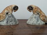 two figurines of two dogs sitting on a rock