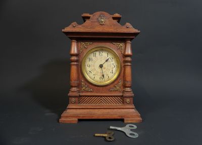 a small wooden clock with a key on a table