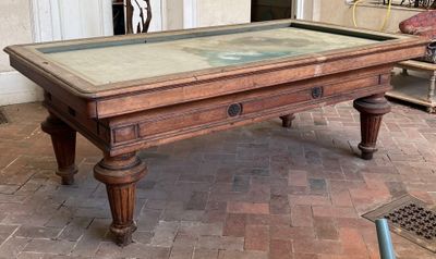 a pool table with a glass top on a brick floor
