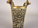an old brass vase with a handle on a white surface