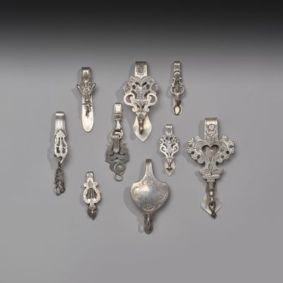 Plusieurs objets argentés sont disposés en rangée sur une surface grise