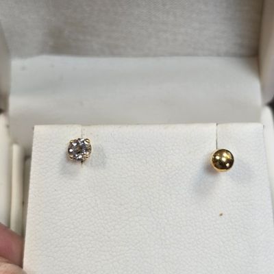 un gros plan sur la main d'une personne tenant une paire de boucles d'oreilles