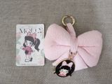 a pink bow keychain with a black and white picture of a girl in a pink dress