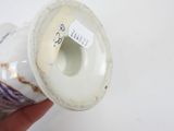 a hand holding a white vase with a label on it