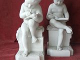 two statues of a boy and a girl sitting on a box