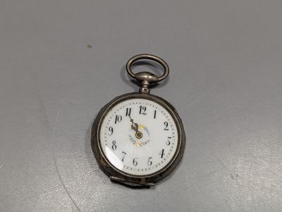 une montre de poche en argent posée sur une table avec un fond blanc